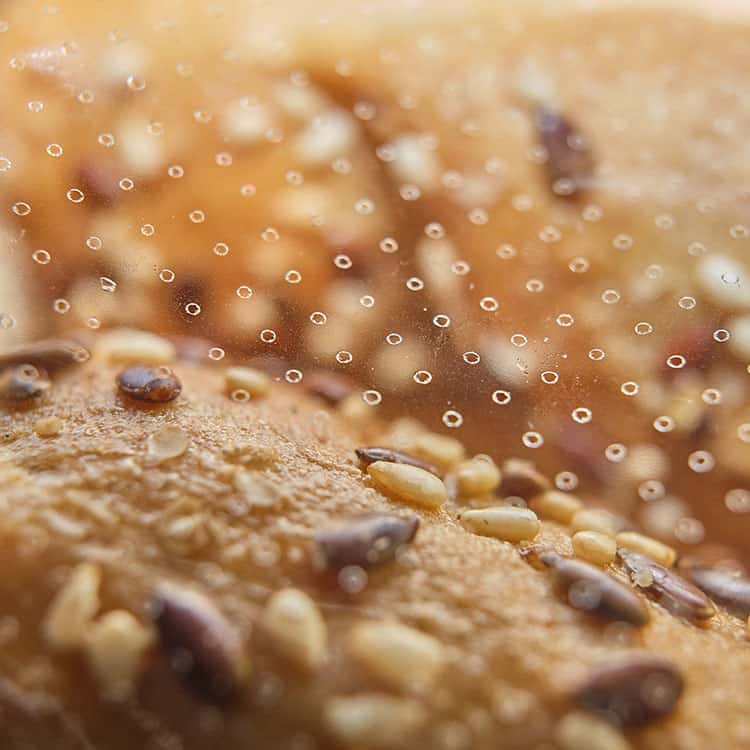 Fresh bread with sesame seeds in perforated breathable laser perforated plastic package close up detailed macro