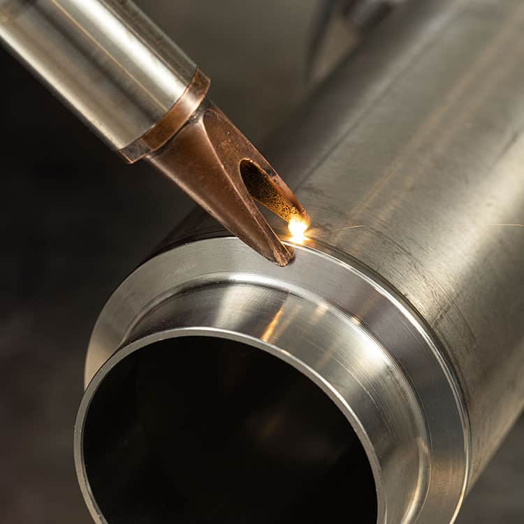 A man in gloves at the enterprise welds metal products by laser welding on a metal workbench. sparks fly