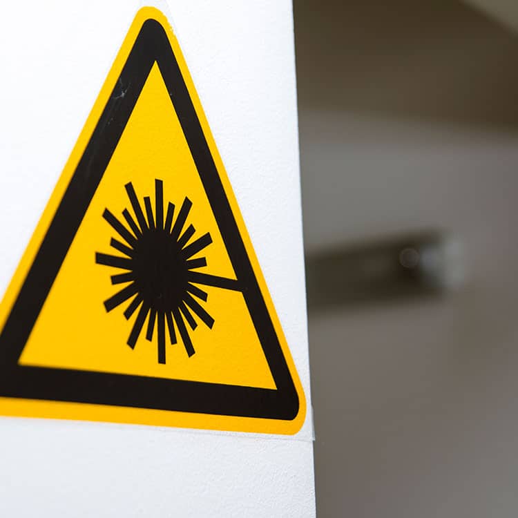 Laser safety warning sticker on a white wall