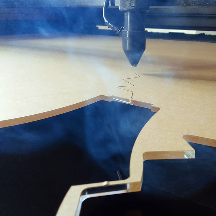 Laser cutting wood with fumes floating in the air